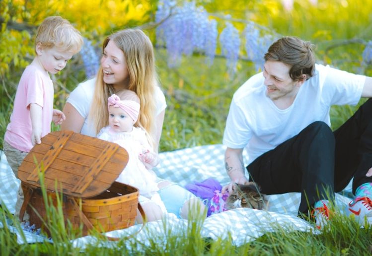 a family sitting on a blanket in the grass